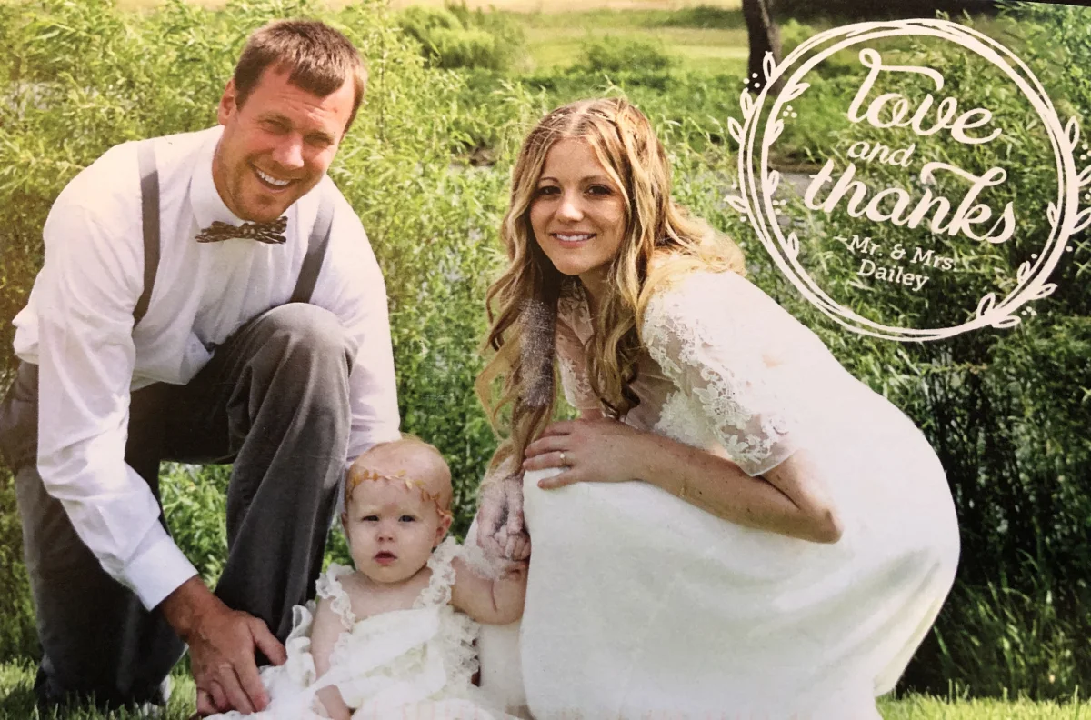 The front of the Daileys' love and thanks card, showing the couple with their baby
